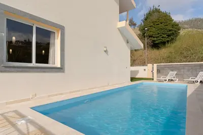 a swimming pool in front of a house at Arco da Calheta Villa in Arco da Calheta