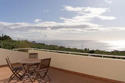 a table and chairs on a balcony with a view of the ocean at Arco da Calheta Villa in Arco da Calheta