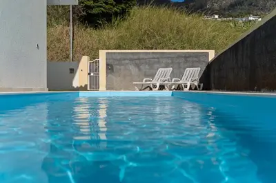 a swimming pool with two chairs and a table at Arco da Calheta Villa in Arco da Calheta