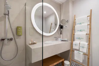 a bathroom with a sink and a shower with a mirror at Aqua Natura Bay in Porto Moniz