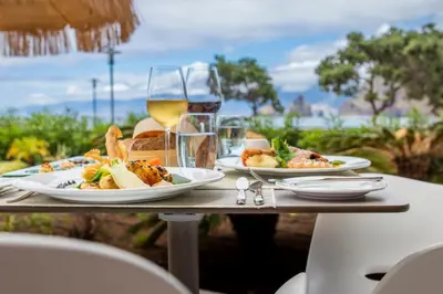 a table with plates of food and a glass of wine at Aqua Natura Bay in Porto Moniz