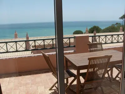 a wooden table and chairs on a balcony with the ocean at Belver Porto Dona Maria Resort in Luz