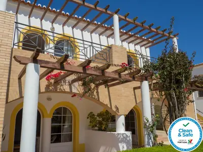 a pergola on a house with flowers on it at Luz Bay Hotel in Luz