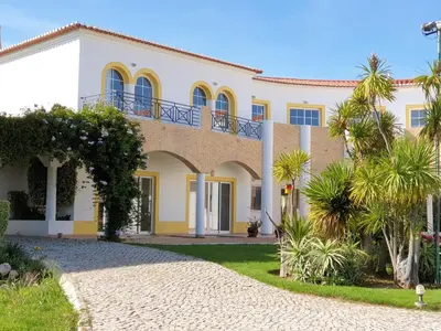 a large white house with a balcony at Luz Bay Hotel in Luz