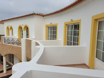 a white house with yellow accents at Luz Bay Hotel in Luz