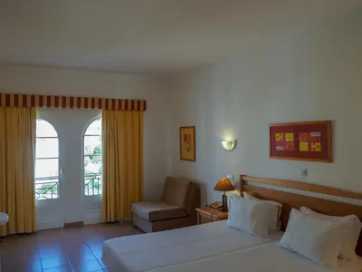 a bedroom with a bed and a chair and a window at Luz Bay Hotel in Luz