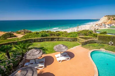 a pool with umbrellas and chairs and the beach at Clube Porto Mos - Sunplace Hotels & Beach Resort in Lagos