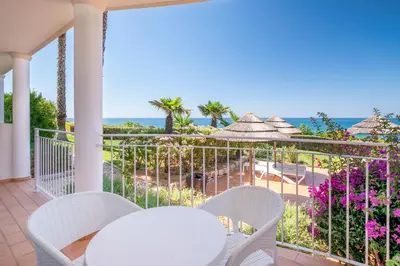 a balcony with a table and chairs and the ocean at Clube Porto Mos - Sunplace Hotels & Beach Resort in Lagos