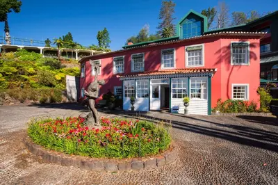 a statue in front of a house with flowers at Quinta do Monte in Funchal