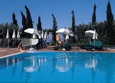 a swimming pool with people sitting on chairs and umbrellas at Quinta do Estreito in Estreito de Câmara de Lobos