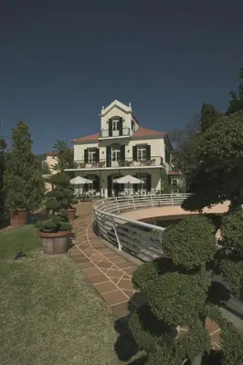 a large white house with a bridge in front of it at Quinta do Estreito in Estreito de Câmara de Lobos
