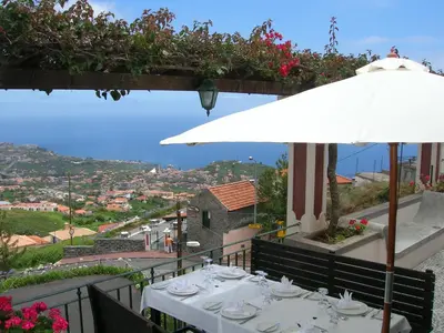a table with a white umbrella and a view at Quinta do Estreito in Estreito de Câmara de Lobos