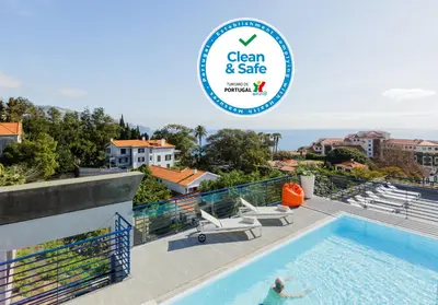 a person swimming in a pool with a sign that reads clean and safe at Terrace Mar Suite Hotel in Funchal