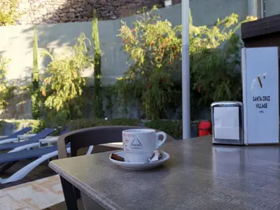 a cup of coffee sitting on a table with a phone at Santa Cruz Village Hotel in Santa Cruz