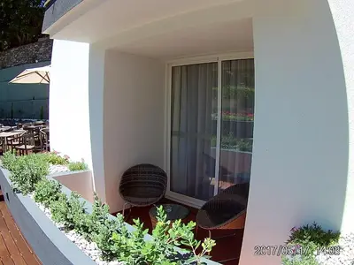 a balcony with wicker chairs and a glass door at Santa Cruz Village Hotel in Santa Cruz