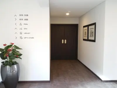 a hallway with a black door and a vase with a plant at Santa Cruz Village Hotel in Santa Cruz