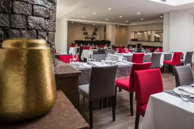 a dining room with tables and red chairs at Santa Cruz Village Hotel in Santa Cruz