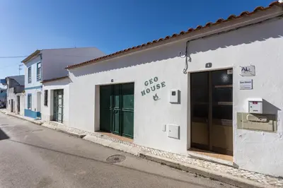 a white building with two doors on a street at Geo House in Vila do Bispo