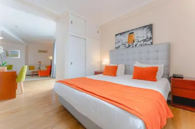a bedroom with a large bed with an orange blanket at Duas Torres Hotel in Funchal