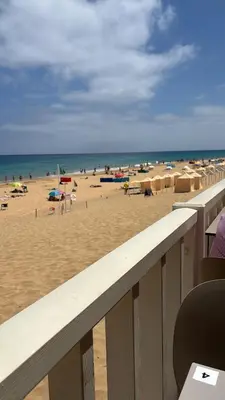 a beach with umbrellas and people on the beach at casa de praia Nunes Village in Porto Santo