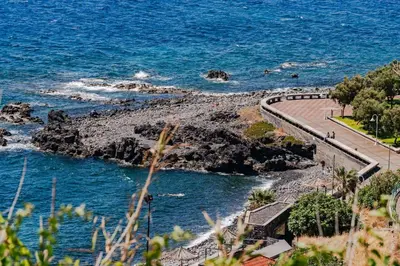 a road next to the ocean next to the water at Apartamento Reis Magos in Caniço