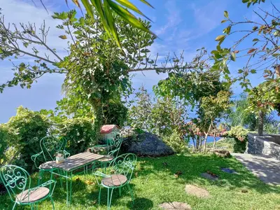 a picnic table and chairs in the grass at Calhau Grande in Arco da Calheta
