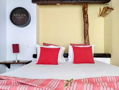 a bedroom with a large bed with red pillows at Calhau Grande in Arco da Calheta