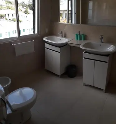 a bathroom with two sinks and a toilet and a window at Villa SCIROCCO Madeira - Ocean View in Machico