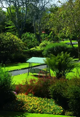 a bench in a garden with flowers and trees at Quinta da Casa Branca - Small Luxury Hotels of the World in Funchal