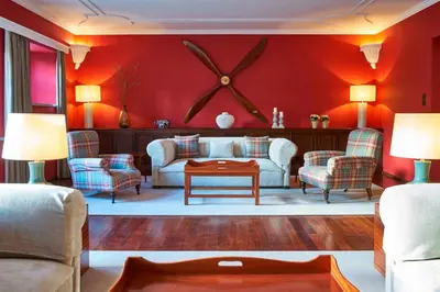 a living room with red walls and a large clock on the wall at Quinta da Casa Branca - Small Luxury Hotels of the World in Funchal