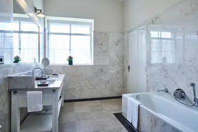 a white bathroom with a tub and a sink at Quinta da Casa Branca - Small Luxury Hotels of the World in Funchal