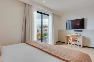 a bedroom with a bed and a desk and a television at The Editory Garden Carmo Funchal in Funchal
