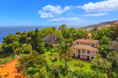 a resort with a pool and chairs and the ocean at Quinta Splendida Wellness & Botanical Garden in Caniço