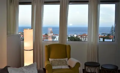 a living room with a yellow chair and large windows at Funchal Window by Homie in Funchal