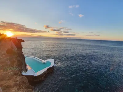 a house on the side of a cliff over the water at Albatroz Beach & Yacht Club in Santa Cruz