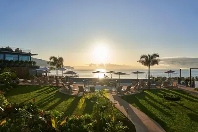 a resort with chairs and umbrellas and the ocean at Les Suites at The Cliff Bay - PortoBay in Funchal