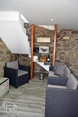a living room with two couches and a stone wall at Palheirinho da Achada in Arco da Calheta