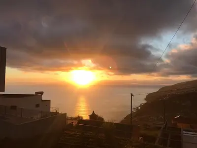 a sunset over the ocean with the sun in the sky at Palheirinho da Achada in Arco da Calheta