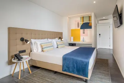 a bedroom with a large bed and a table at Allegro Madeira - Adults Only in Funchal