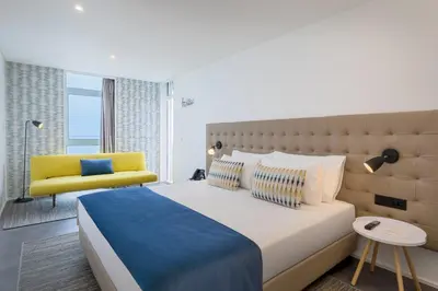 a bedroom with a large bed and a yellow chair at Allegro Madeira - Adults Only in Funchal