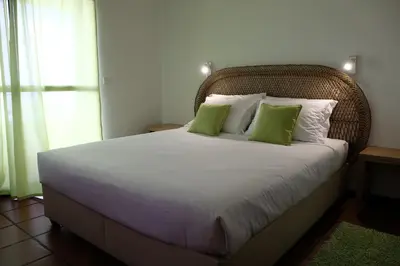 a bedroom with a large bed with green pillows at Apartamentos Quinta Mae dos Homens in Funchal