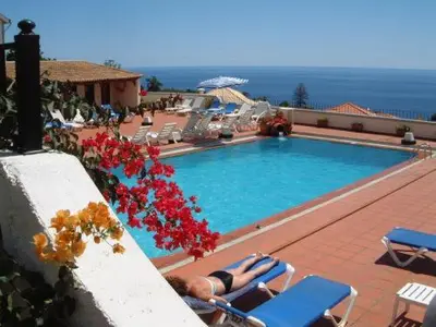 a woman laying in lounge chairs next to a swimming pool at Apartamentos Quinta Mae dos Homens in Funchal