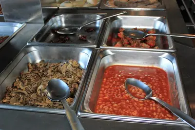 a buffet with four trays of food with spoons at Eira do Serrado - Hotel & Spa in Curral das Freiras