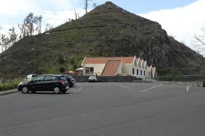 a parking lot with a building and a mountain at Eira do Serrado - Hotel & Spa in Curral das Freiras