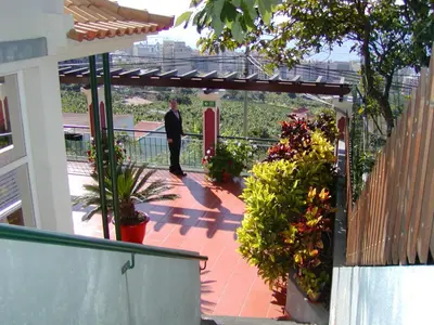 a man in a suit walking on a patio with flowers at Vila Marta in Funchal