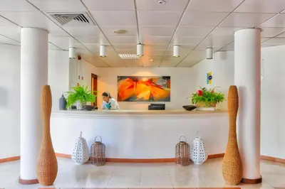 a lobby with a woman standing at a reception counter at Hotel Torre Praia in Porto Santo