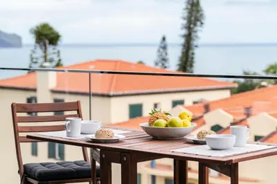 a wooden table with a bowl of fruit on a balcony at Funchal Lux I by An Island Apart in Funchal