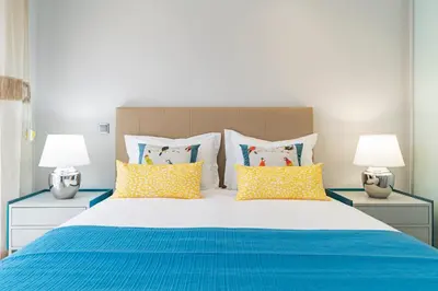 a bedroom with a large bed with blue and yellow pillows at Funchal Lux I by An Island Apart in Funchal