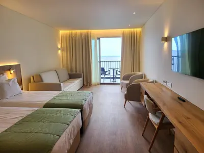 a hotel room with two beds and a desk and a table at Hotel Royal Orchid in Caniço