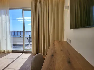 a dining room with a wooden table and a large window at Hotel Royal Orchid in Caniço